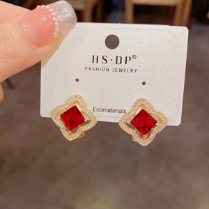 Détail de boucles d'oreilles trèfle rubis avec placage or et incrustation de zircon