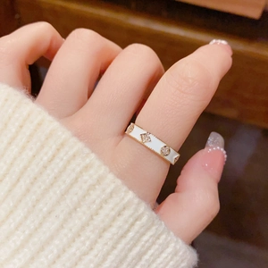Détail d'une bague fleur dorée avec émail blanc et cristaux sur la main du modèle