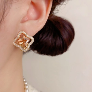 Gros plan d'une boucle d'oreille trèfle dorée avec zircon champagne et pierres pavées
