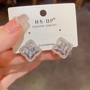 Gros plan d'une boucle d'oreille trèfle avec diamant central et cristaux en micro-pavage