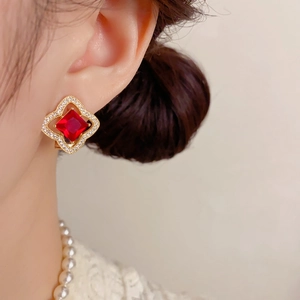 Vue macro détaillée de boucles d'oreilles trèfle en or avec zircon rouge et micro-pavage