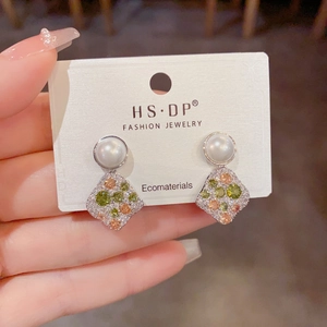 Detailed close-up of diamond-encrusted silver earrings with pearls and colorful gemstones