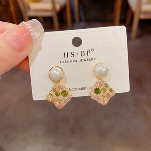 Detail of elegant gold earrings with white pearl and colorful pavé cubic zirconia pendant