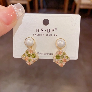 Detailed shot of gold-plated pearl earrings with colorful cubic zirconia on display card