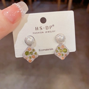 Detailed close-up of diamond-encrusted rhombic pendant earrings with white pearls