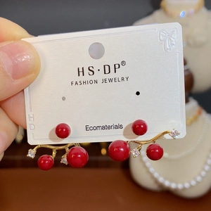 Macro detail of red pearl branch earrings with crystal zircon on a jewelry card
