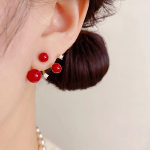 Close-up of elegant red pearl earrings with sparkling zircons on a model ear