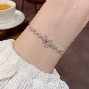 Sparkling silver bow bracelet with heart-shaped zircon stones on elegant lace sleeve