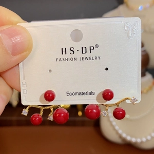 Detail of gold-plated earrings with red pearls and sparkling cubic zirconia accents