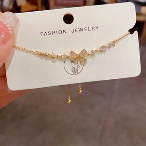 Macro shot of gold bow bracelet with heart-shaped cubic zirconia and fashion jewelry tag