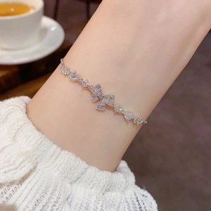 Detailed view of an elegant bow bracelet with zircon stones worn by a female model