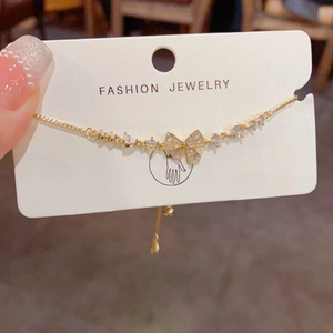 Close-up of golden bow bracelet with micro-paved cubic zirconia and adjustable chain