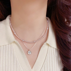 Détail d'un collier double rang avec perles roses et pendentif zircon sur le cou