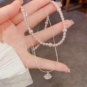 Gros plan sur un collier double rang avec perles blanches et un pendentif en cristal