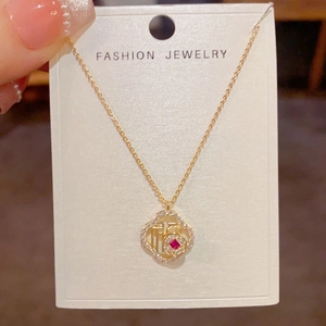 Detalle del collar con colgante Fu dorado con gema roja y marco de circón en tarjeta