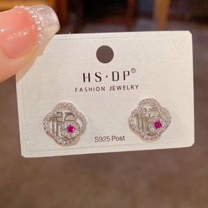 Detalle de pendientes de plata S925 con el símbolo Fook y diseño de trébol de cristal