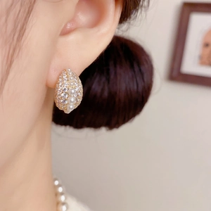 Detailopname van elegante oorbellen met kleine parels en kristallen op gouden metaal