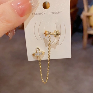 Detail of a vintage gold cross ear cuff with chain tassel and sparkling zircon inlays