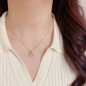 Detail of elegant gold necklace with geometric crystal pendants on a model's neckline