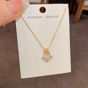 Detail of gold necklace featuring triple-row crystal pendants and zircon drop accents
