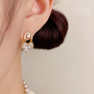 Close-up of gold heart drop earrings with sparkling cubic zirconia on female model