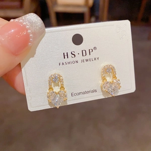 Macro view of gold plated heart earrings with clear zircon stones on jewelry card