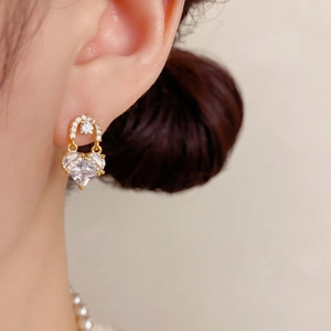 Close-up of elegant gold plated heart stud earrings with cubic zirconia on female model