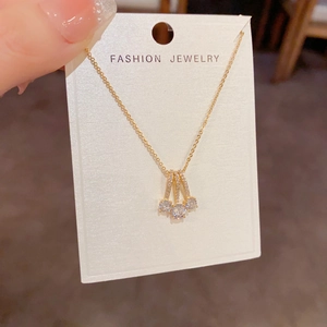 Close-up of gold geometric pendant necklace with three diamonds on display card