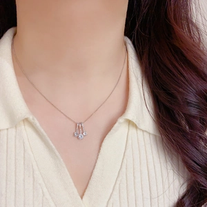 Detailed view of a silver geometric pendant necklace with three sparkling zircons on a model