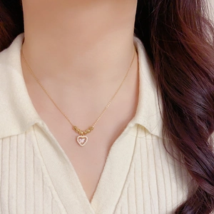 Gros plan du collier pendentif coeur rose avec perles dorées sur la clavicule