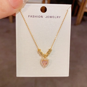 Détail du collier cœur rose avec perles dorées et cristaux sur carte de présentation
