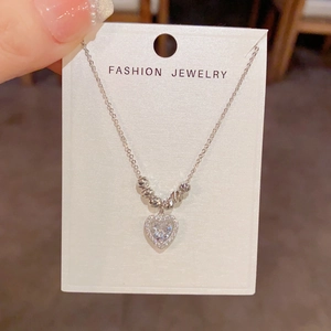 Détail du pendentif cœur argenté avec pavé de cristaux et perles sur une carte cadeau
