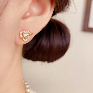 Élégantes boucles d'oreilles cœur planète dorées avec zircons sur une oreille femme