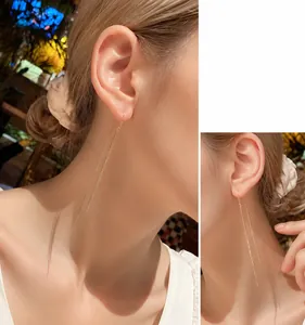 Detail view of long golden chain tassel earrings with shimmering metal fringe on a model