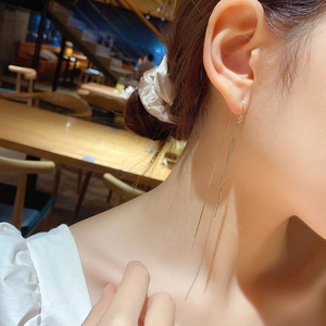 Elegant gold chain tassel drop earrings for women shown worn on ear for draped effect