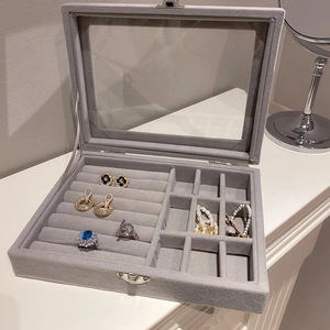 Detail of grey velvet jewelry box with glass lid showing multi-slot ring and earring storage