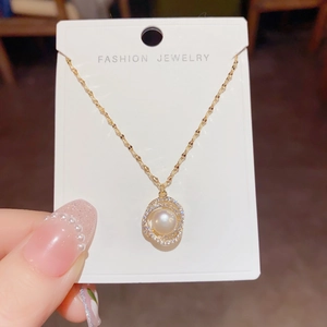 Detailed close-up of a golden necklace featuring a pearl pendant with a zircon halo