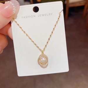 Macro detail of gold necklace with zircon-encrusted rings around a freshwater pearl