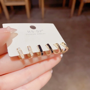 Detail van drie paar 18K vergulde oorringen met strassteentjes en zwart emaille op kaart
