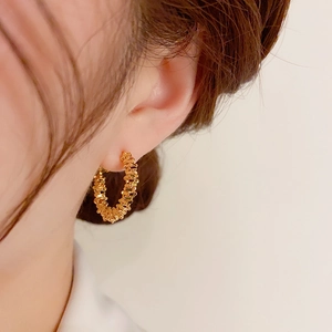 Élégantes créoles en or 18 carats avec texture tressée portées par un mannequin