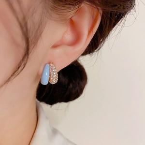 Macro detail of elegant double-loop hoop earrings with light blue enamel and pavé zircons