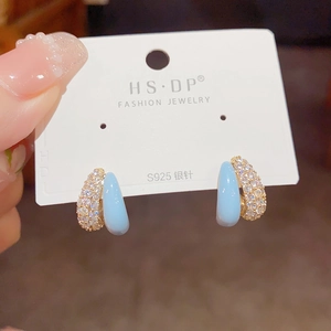 Detail of light blue enamel and zircon studded gold hoop earrings on S925 silver pins