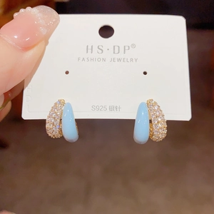 Detail of light blue enamel and sparkling white zircon pavé on gold-plated hoop earrings