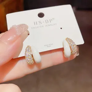 Detail of gold hoop earrings with sparkling micro-pave cubic zirconia and white enamel