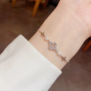 Elegant silver clover bracelet with sparkling zircons and white pearls on woman wrist