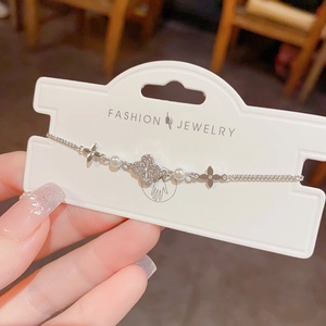 Silver bracelet with hollow diamond-set clovers and white pearls on delicate chain