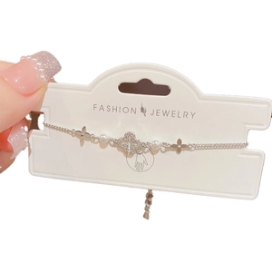 Elegant silver clover bracelet with inlaid crystals and pearls on white background