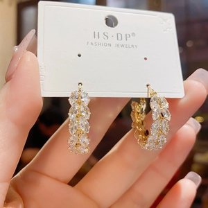 Close-up of gold hoop earrings with sparkling wheat-shaped cubic zirconia on a card