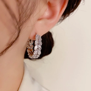 Elegant silver zircon hoop earrings with leaf pattern shown on a female model