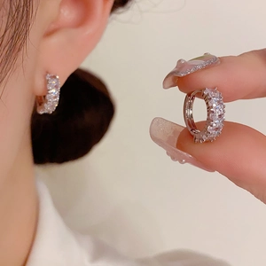 Macro detail of silver zircon hoop earrings featuring clear stones on a mini circular band